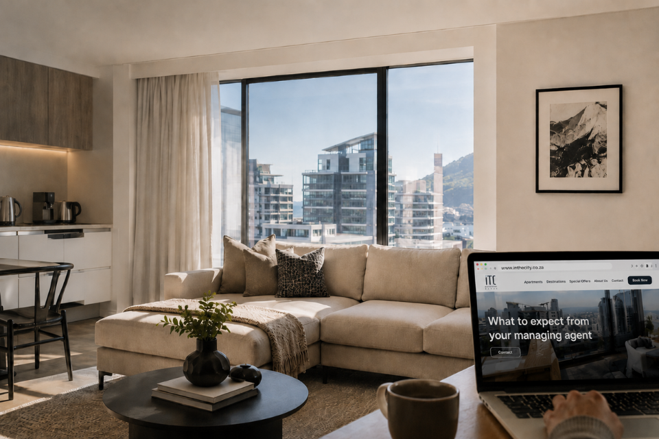 Modern, sunlit apartment living room overlooking Cape Town's skyline, with a laptop displaying ITC Hospitality Group's "What to Expect from Your Managing Agent" webpage, highlighting secure property management and booking fraud prevention.
